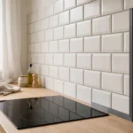 A bright kitchen scene, a tiled backsplash with a neat matte charcoal-gray 3D printed edge trim covering the exposed end row of tiles, a countertop