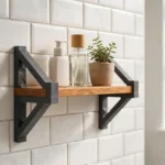 A bright bathroom scene, a small wooden shelf on a tiled wall held by two matte charcoal-gray 3D printed shelf brackets