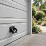 A garage door exterior scene, a matte black 3D printed pull handle mounted on a light gray sectional garage door
