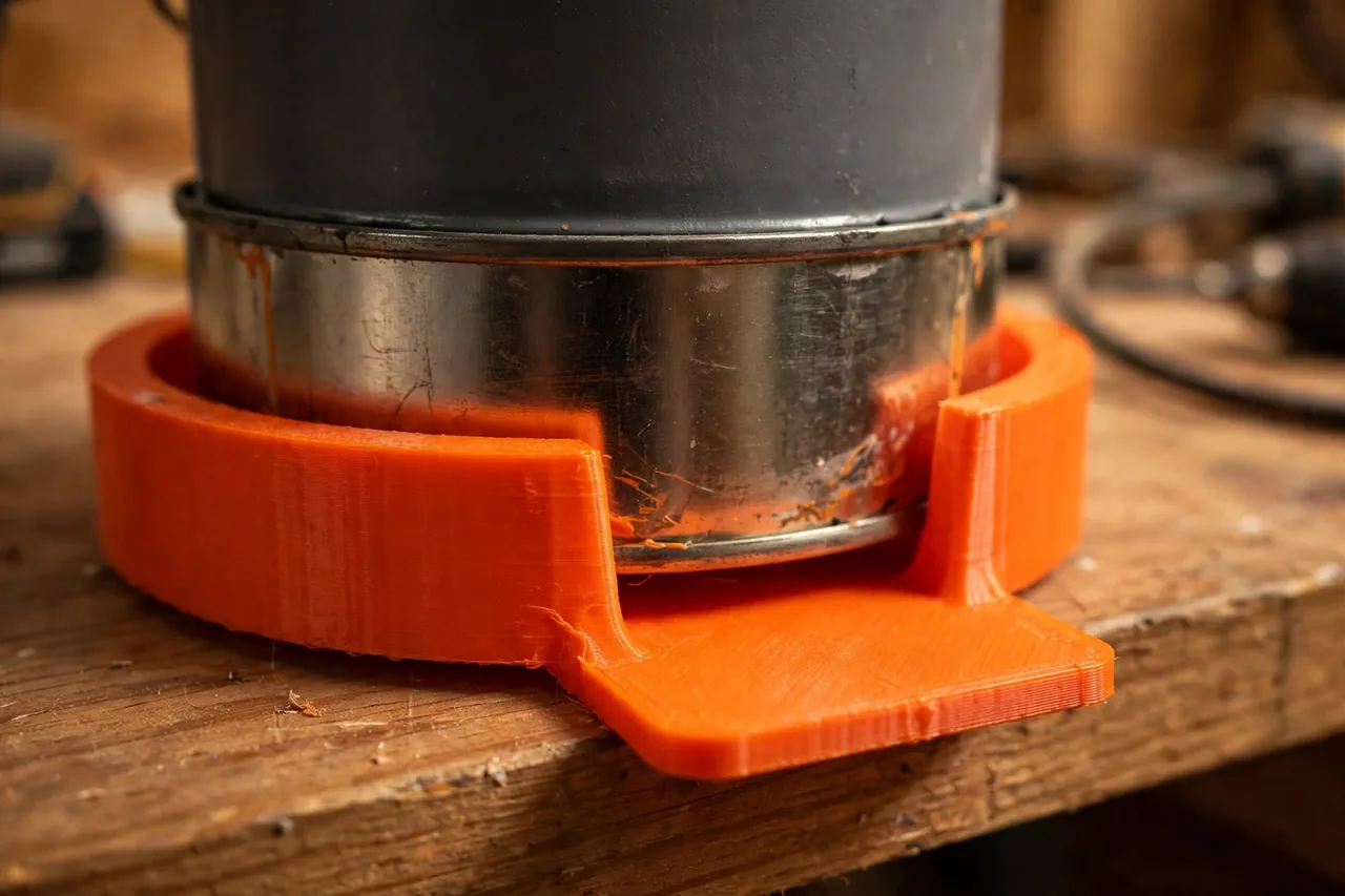Close-up view of a bright-orange 3D printed can cradle ring supporting the base of a quart paint can