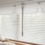 A bright living room window with white horizontal blinds in soft daylight