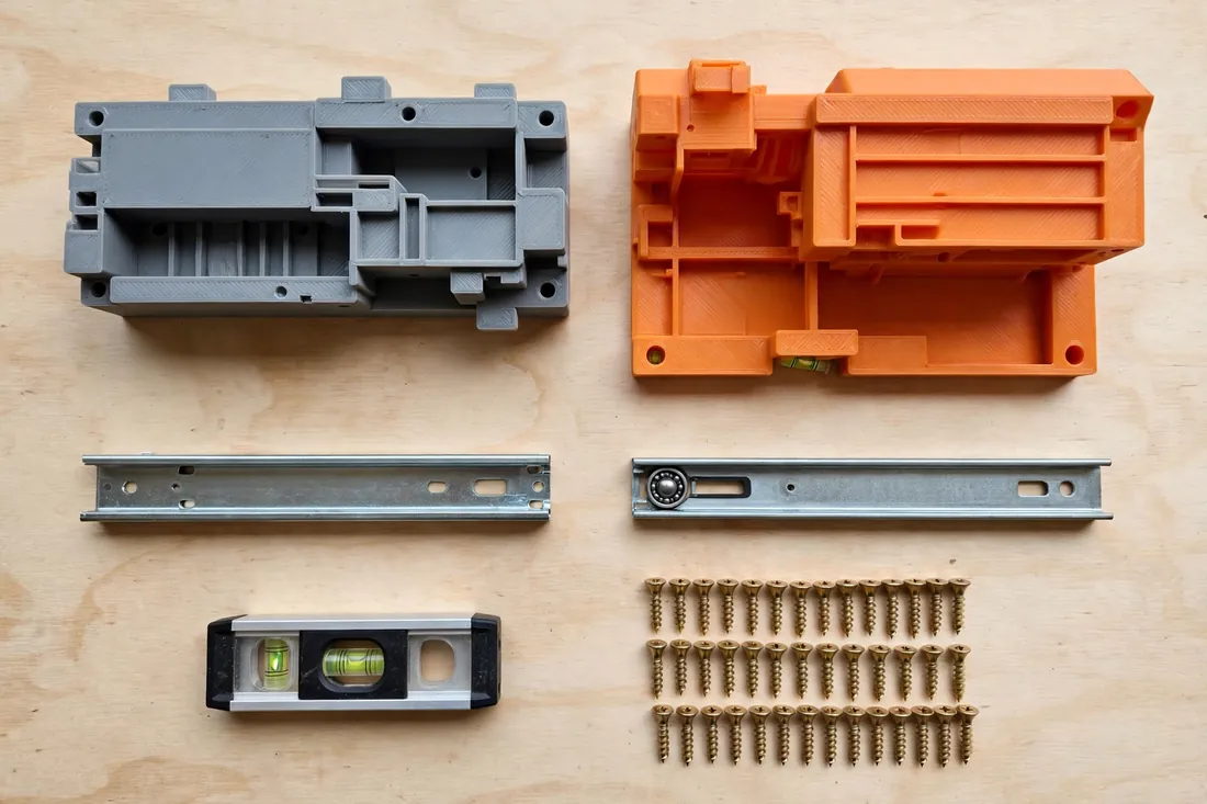 Top-down view of a workbench with two matching 3D printed drawer slide jigs in matte gray and orange