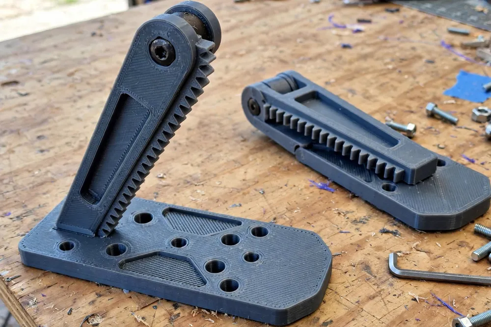 Close-up of a 3D printed solar panel kickstand leg on a workbench showing its indexed angle teeth, hinge knuckle and wide flat foot